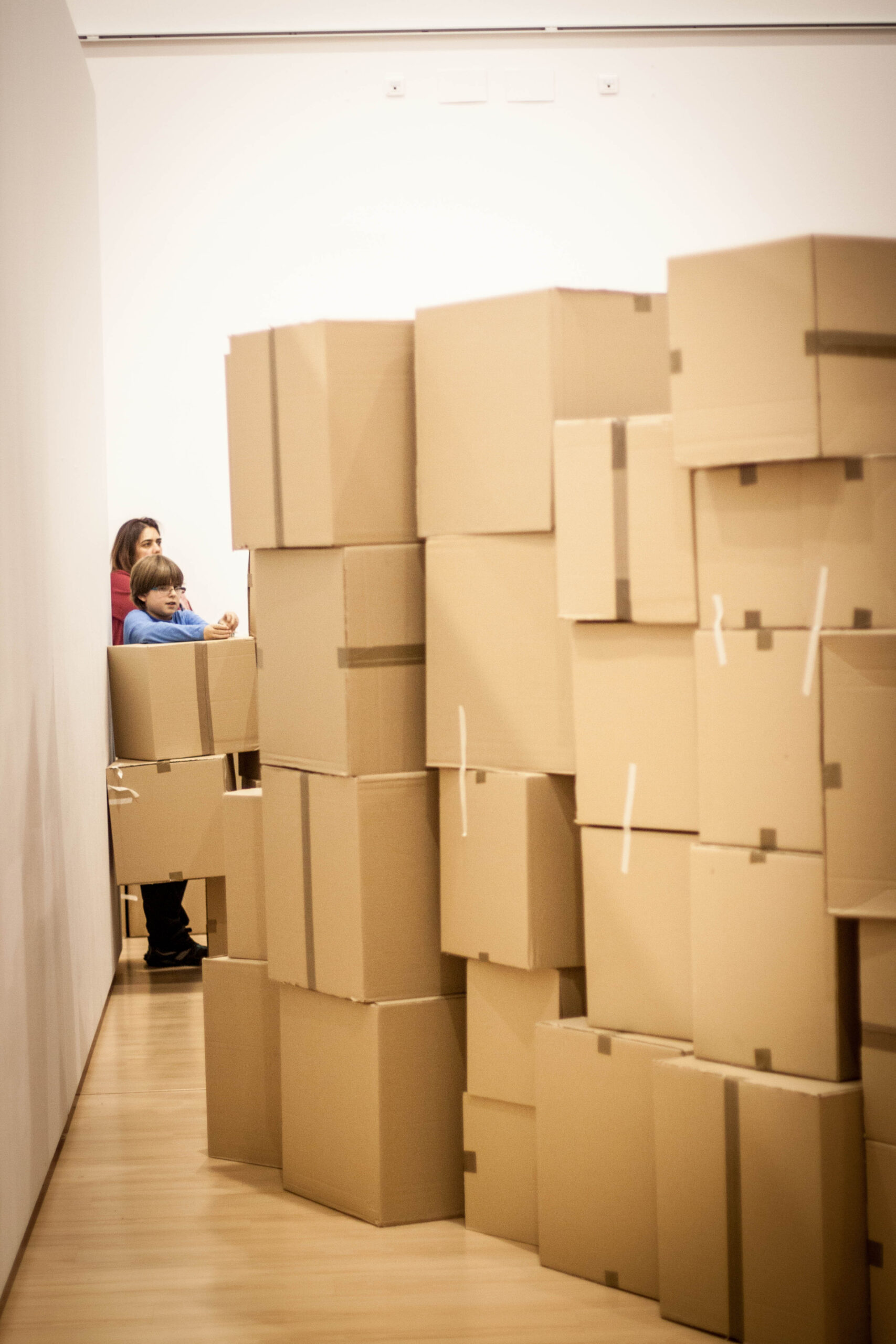 Niña entre un muro alto de cajas de cartón.