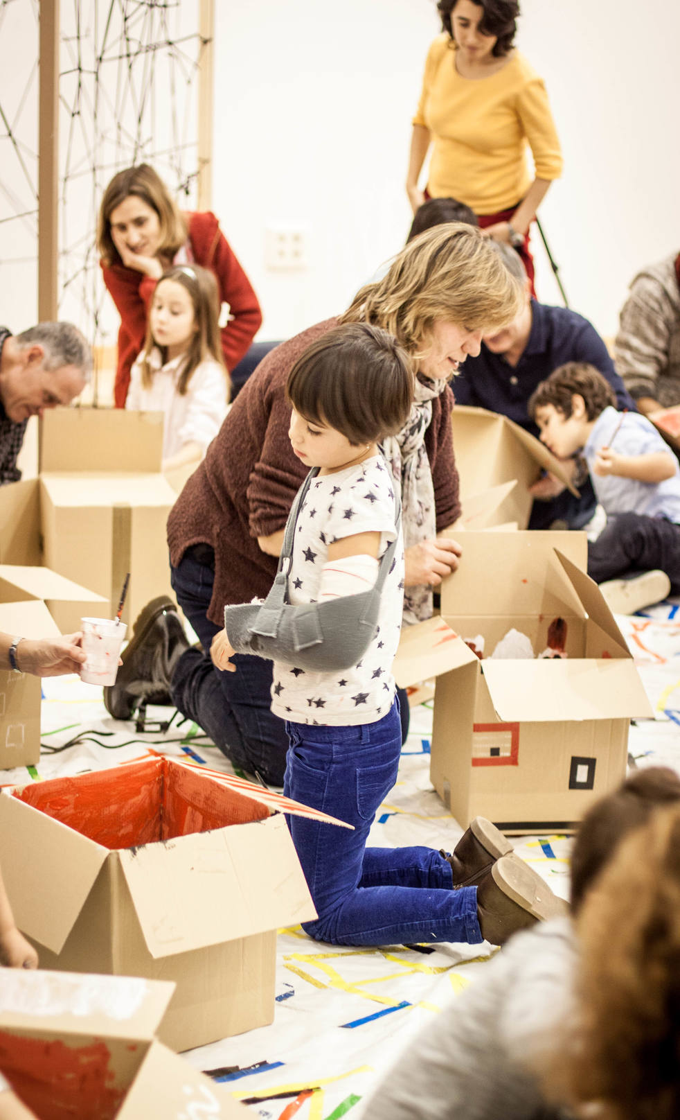 Niñas y niños creando entre cajas y materiales de dibujo.
