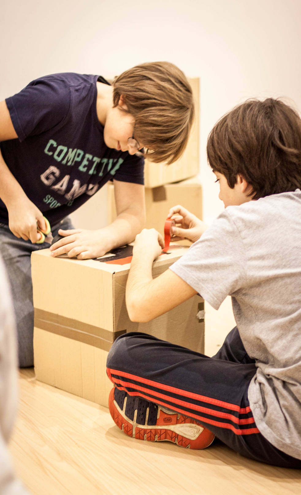 Dos niños dibujando sobre un módulo de cartón.
