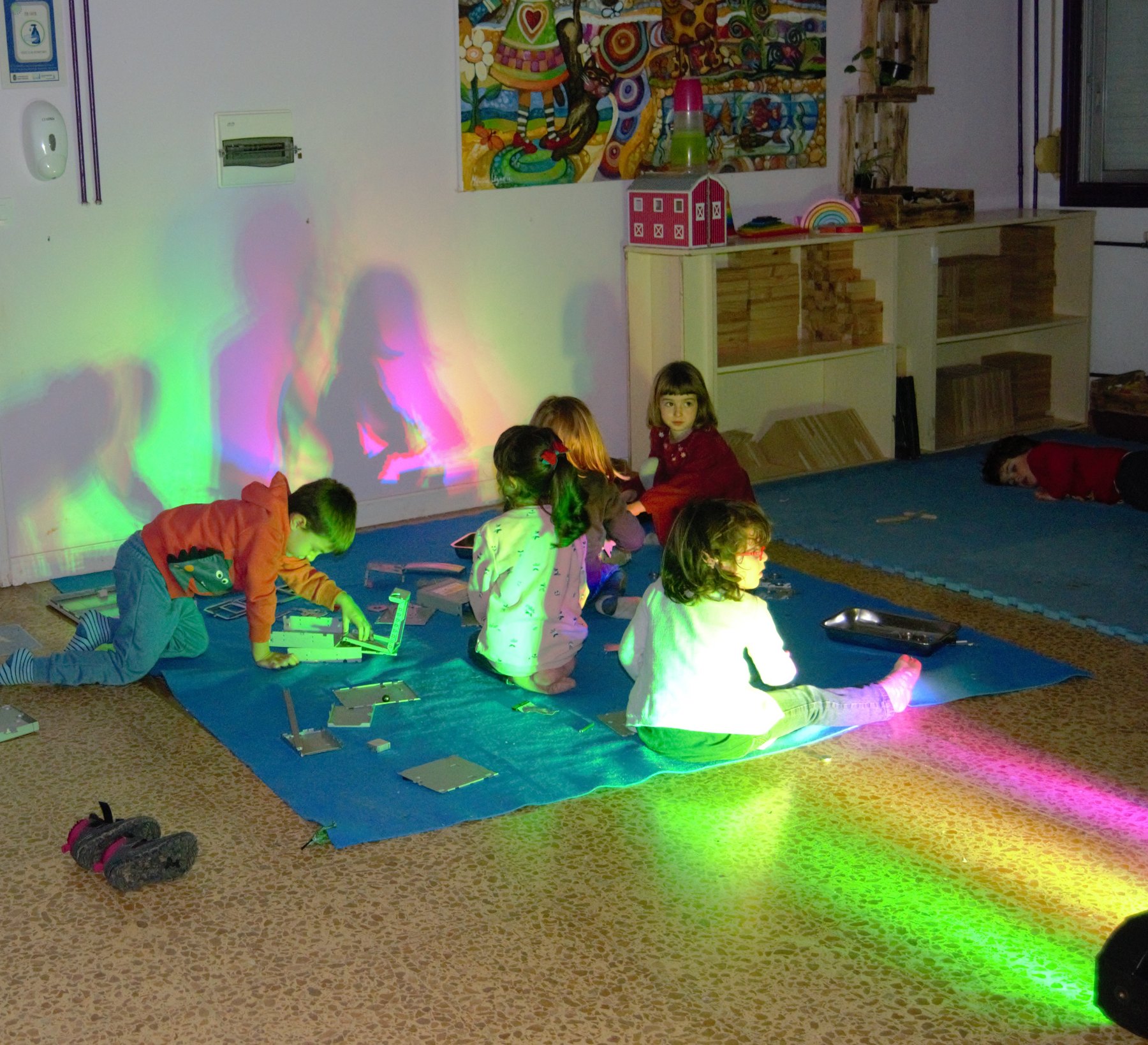 Grupo infantil explora haces de luz de colores.