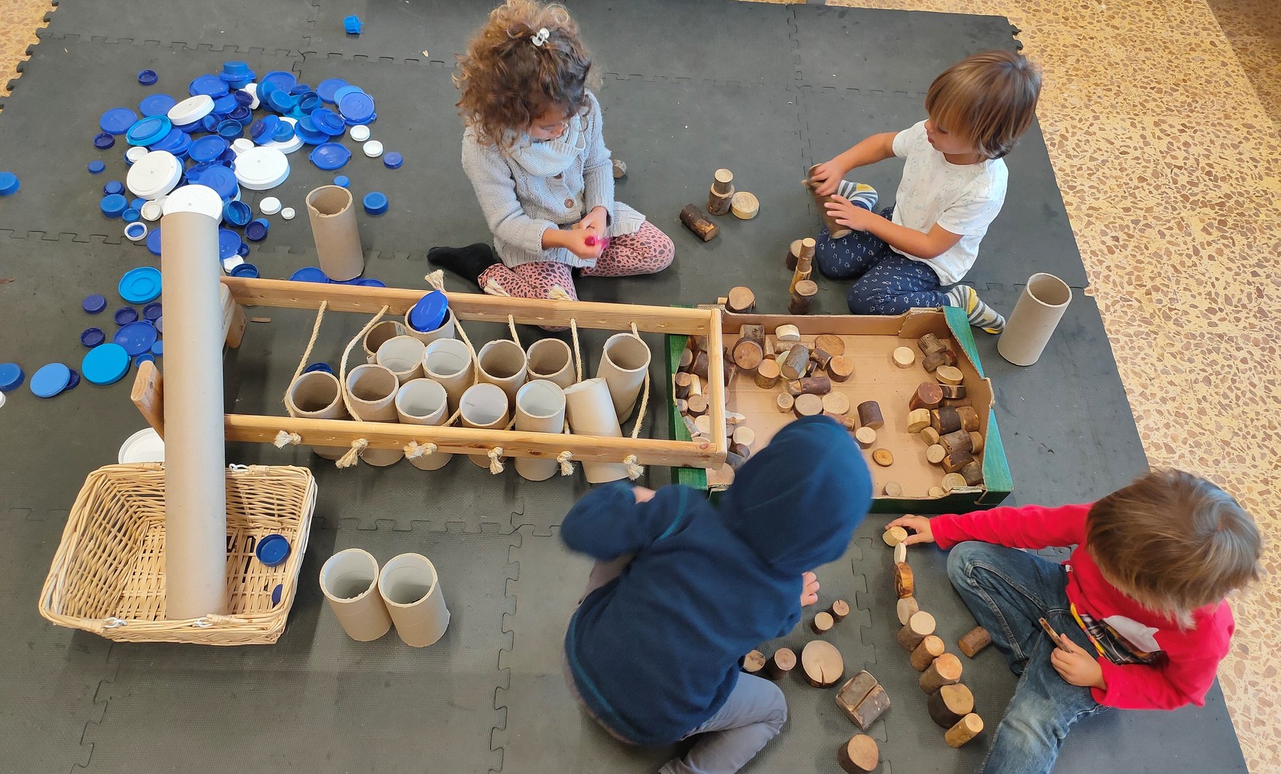 Grupo infantil construye con tubos, discos y piezas de madera.
