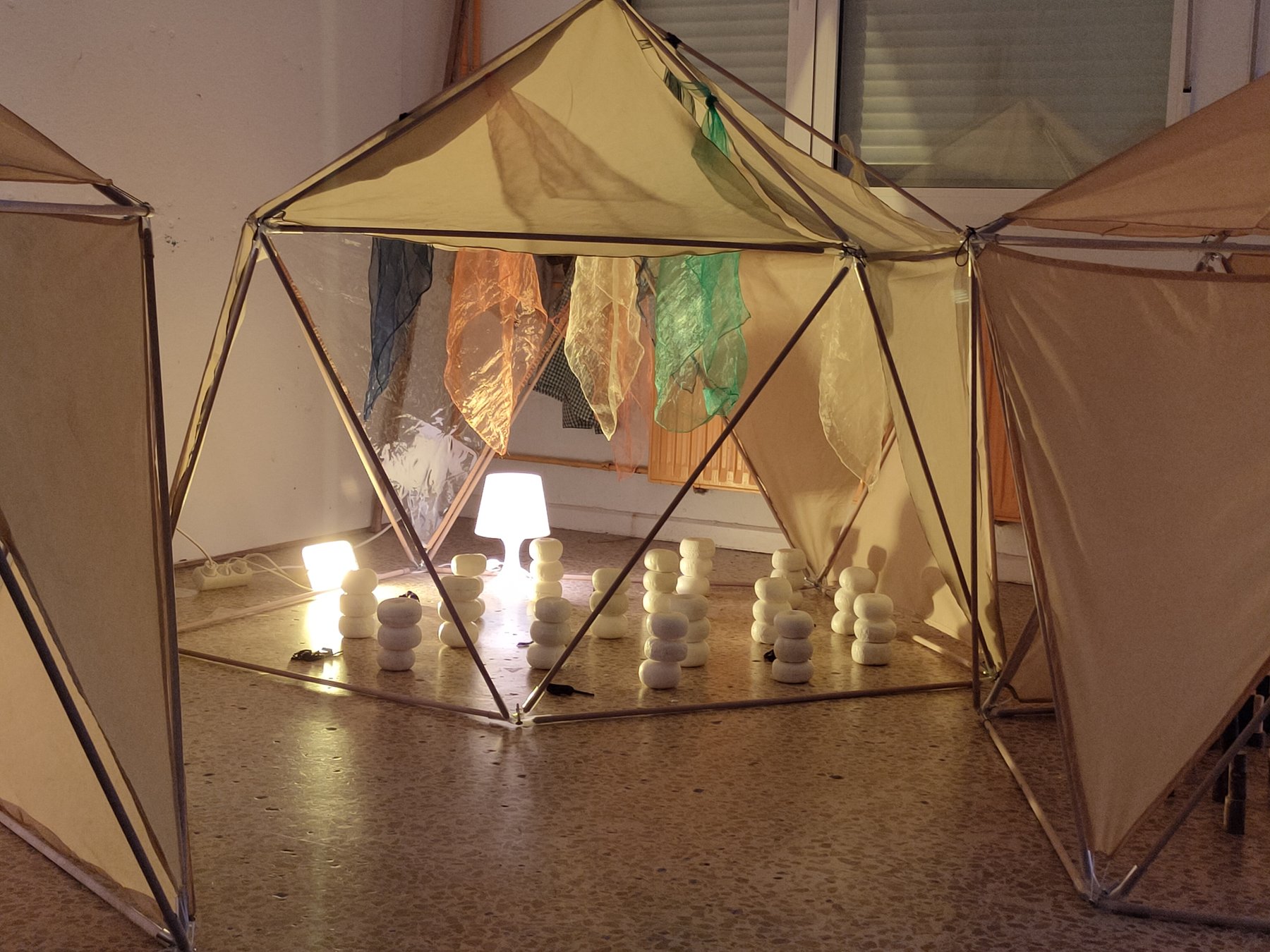 Estructura geodésica iluminada con piezas blancas apiladas y tejidos translúcidos.