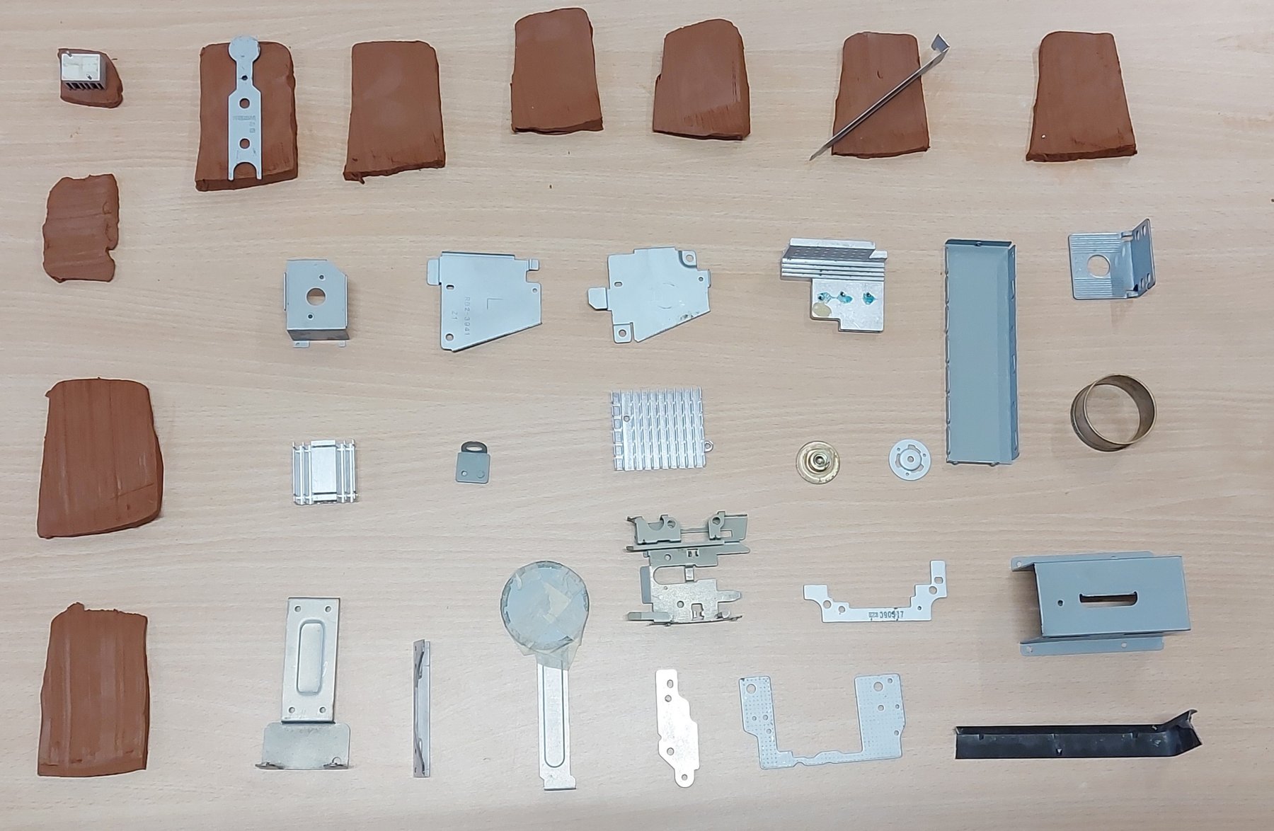 Componentes metálicos de aparatos y piezas de arcilla ordenados sobre una mesa.