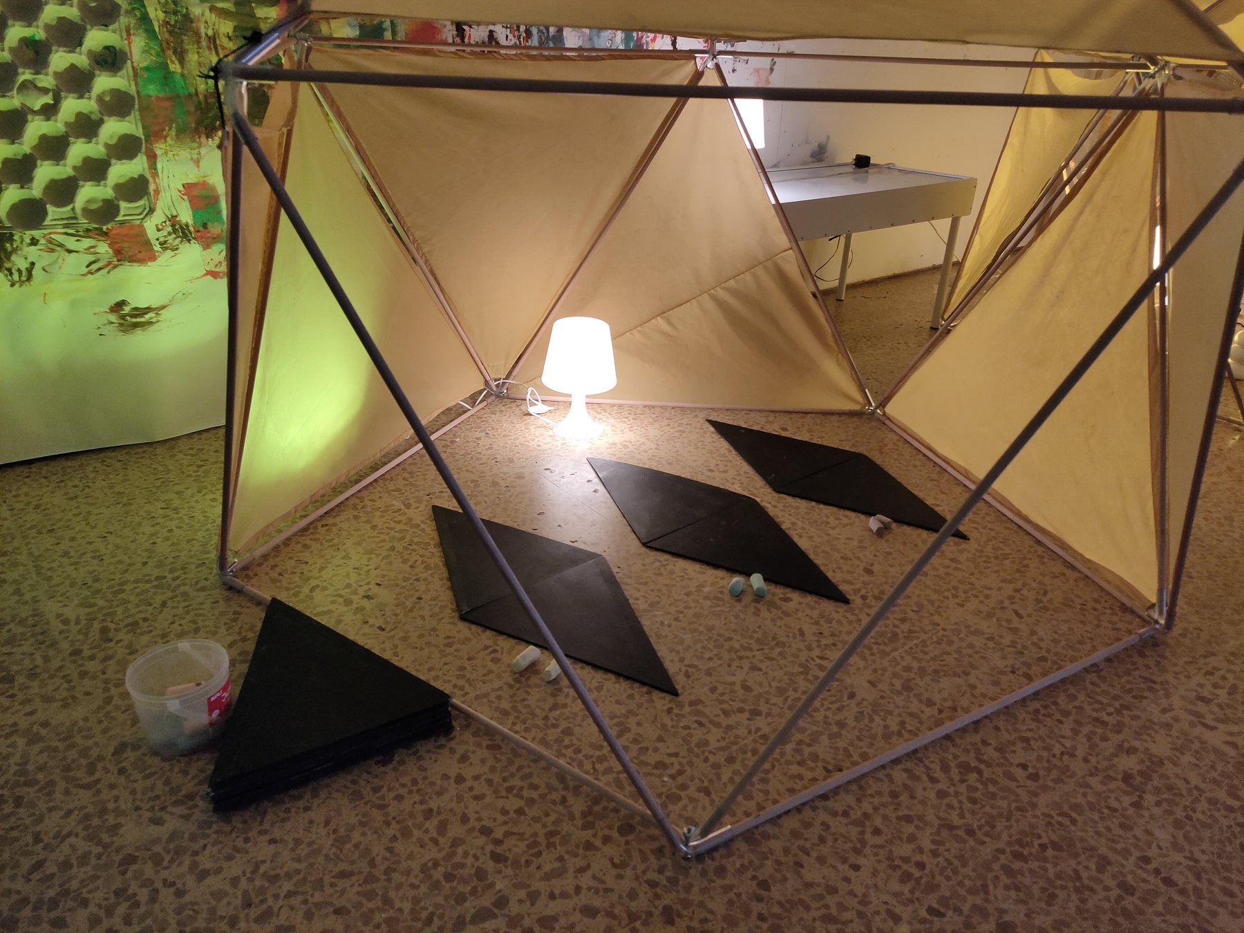 Estructura geodésica abierta con módulos negros, luz y una proyección sobre el tejido.
