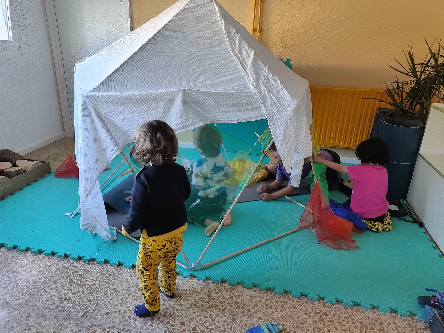Niños se aproximan a una pequeña estructura cubierta inicialmente con un tejido blanco.