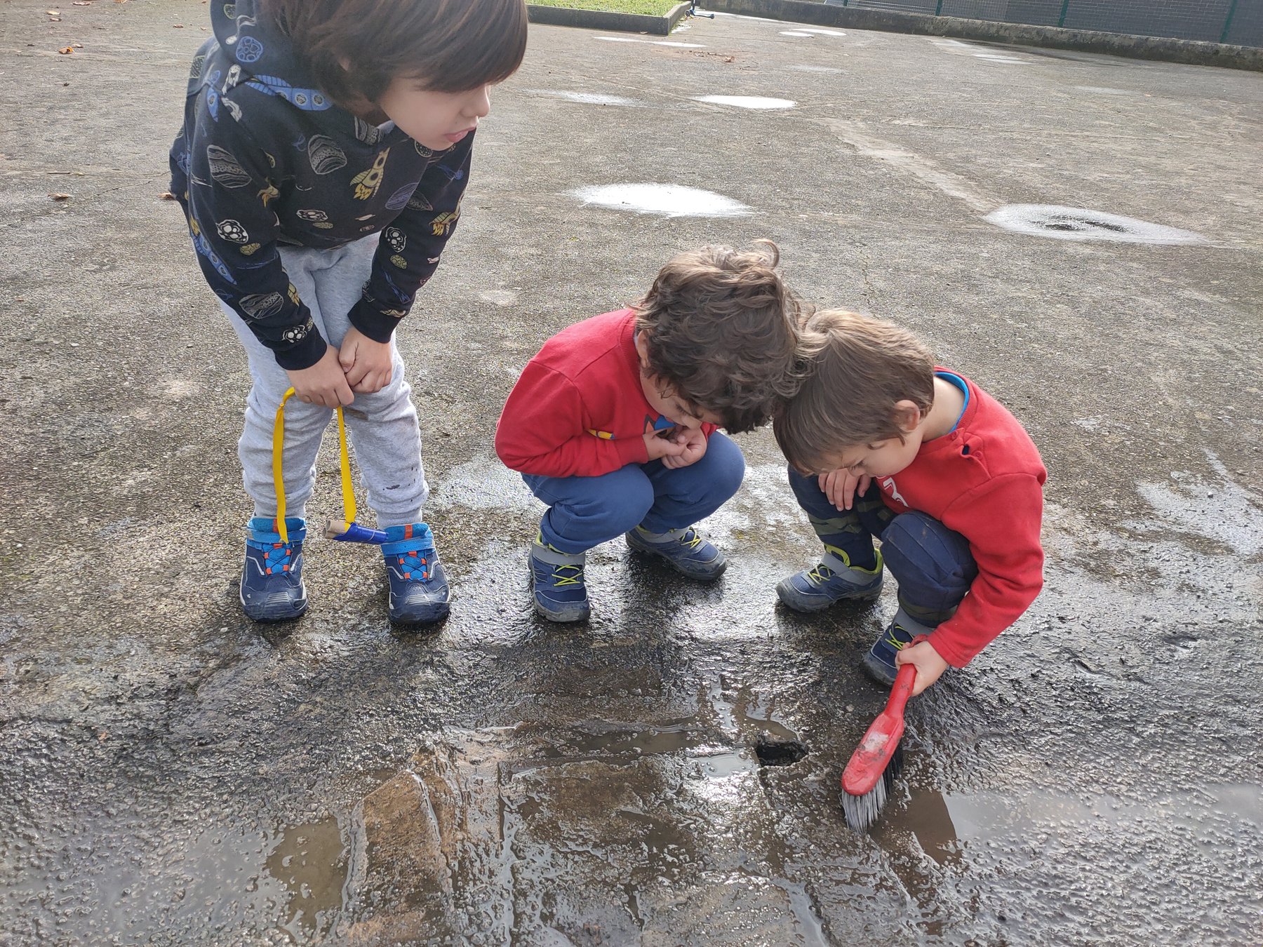 Niños investigan agua y marcas gráficas en el patio.