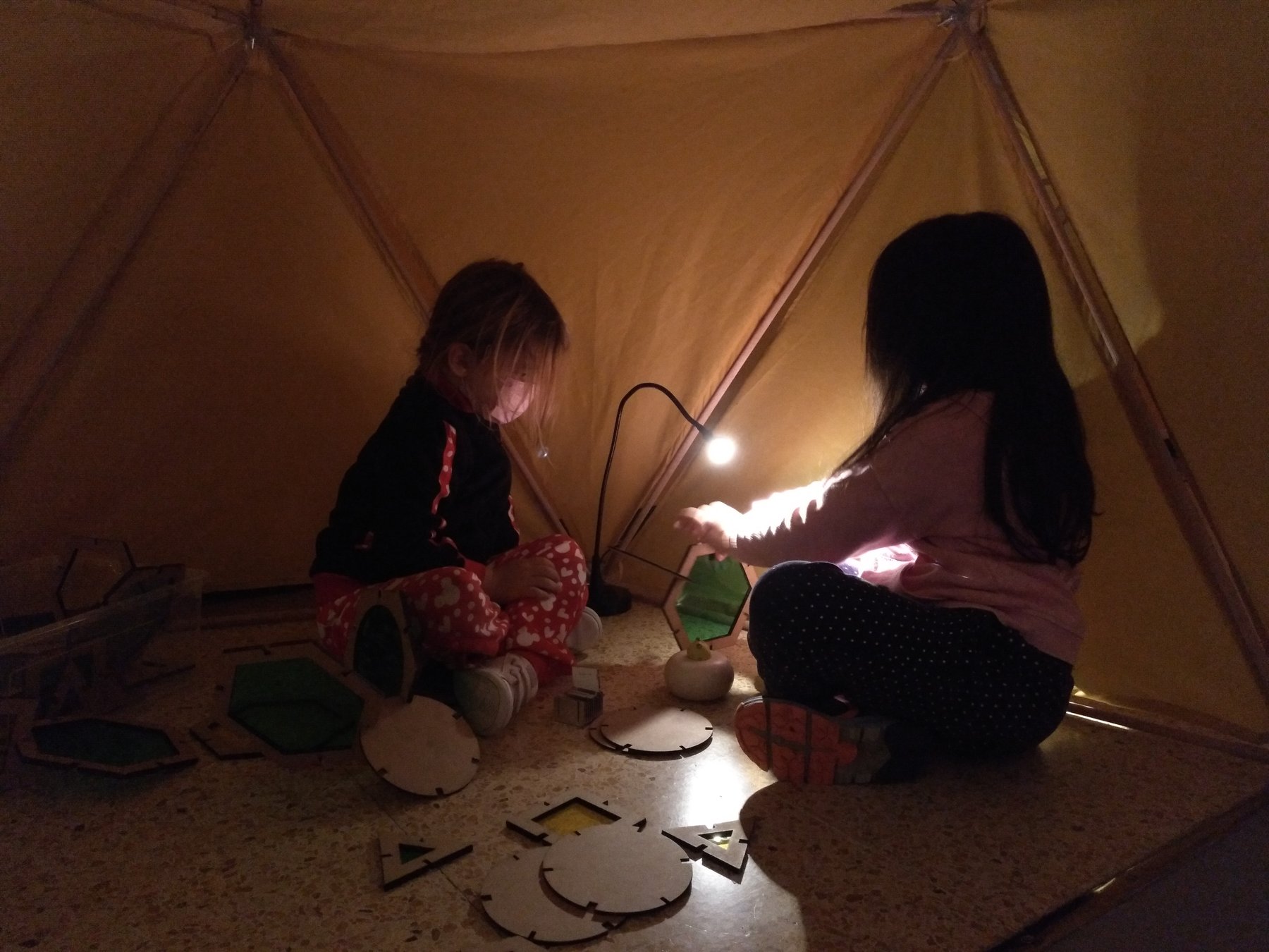 Dos niñas exploran objetos iluminados dentro de un domo.