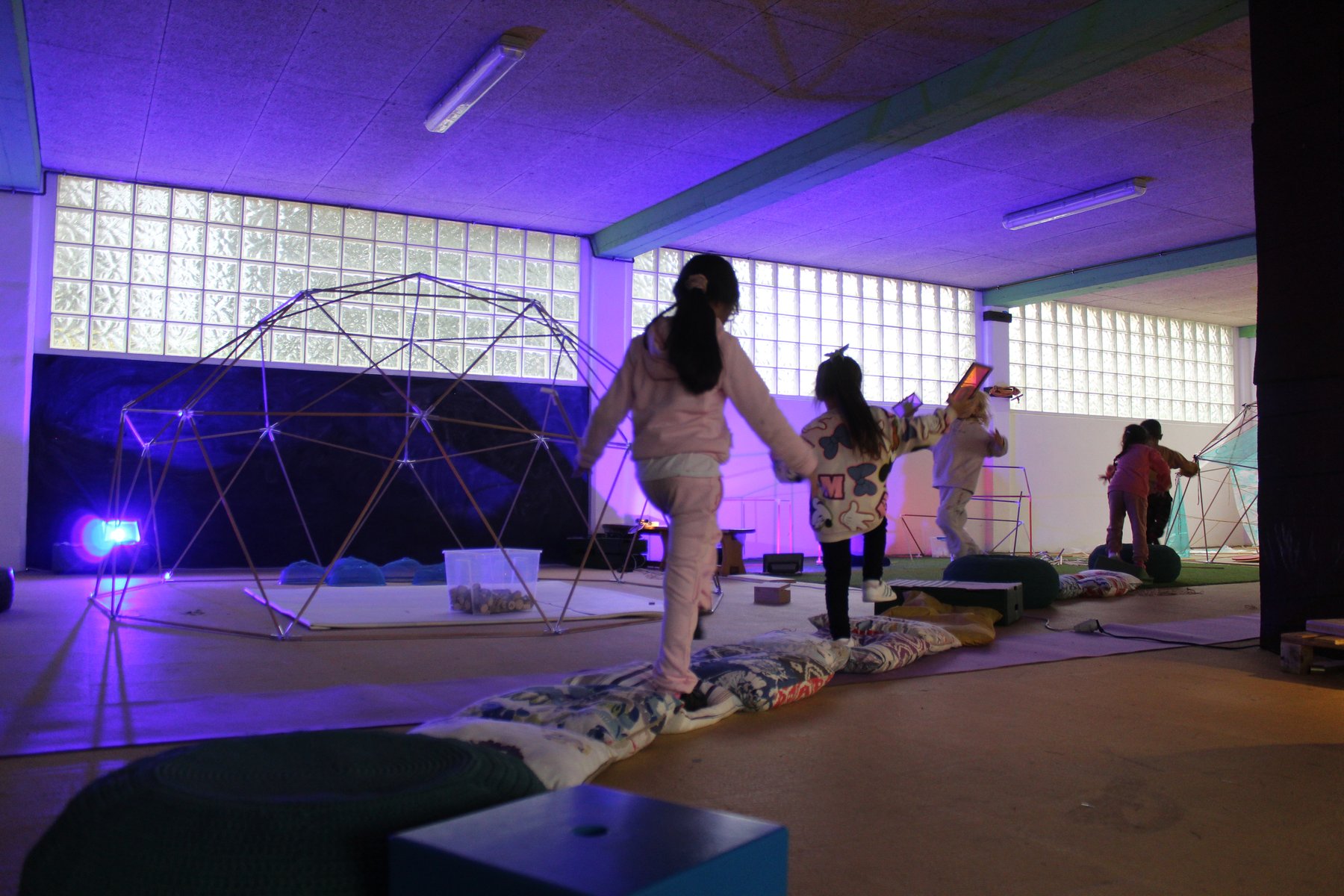 Niñas y niños exploran los reflejos y transparencias de la instalación Irisada.