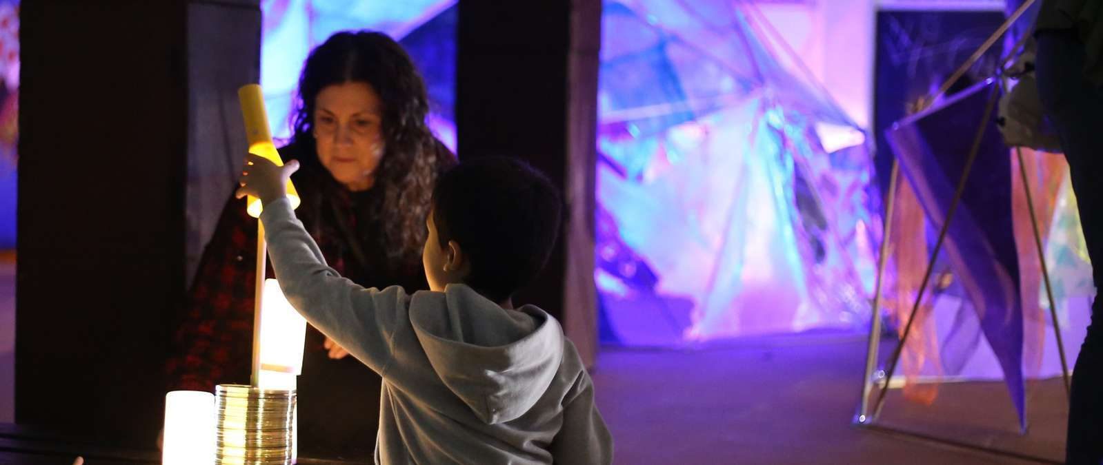 Niña observando una proyección de luz sobre una superficie transparente en Irisada.