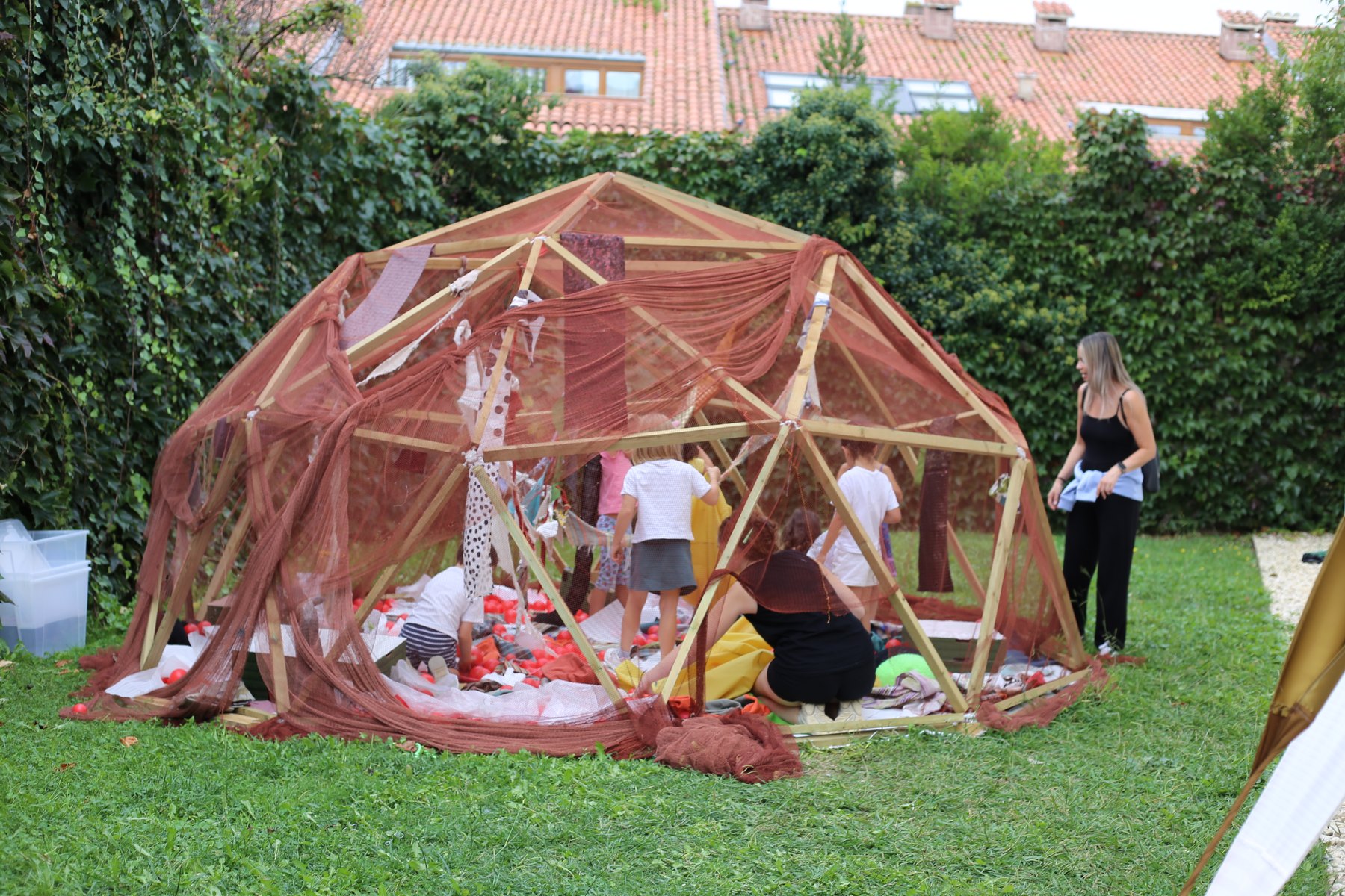 Familias jugando dentro de la estructura geodésica cubierta con una red rojiza.