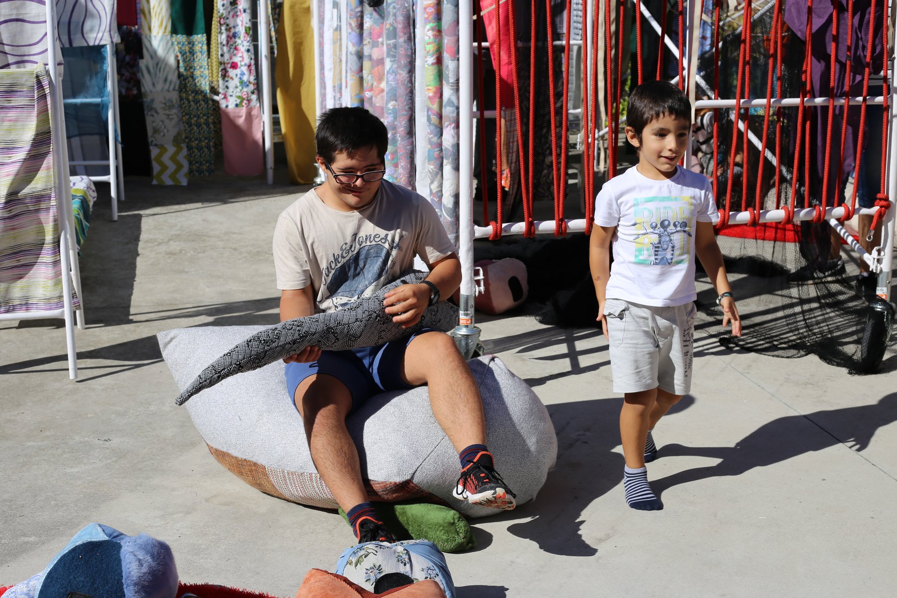 Niños jugando con formas textiles blandas junto a una trama suspendida.