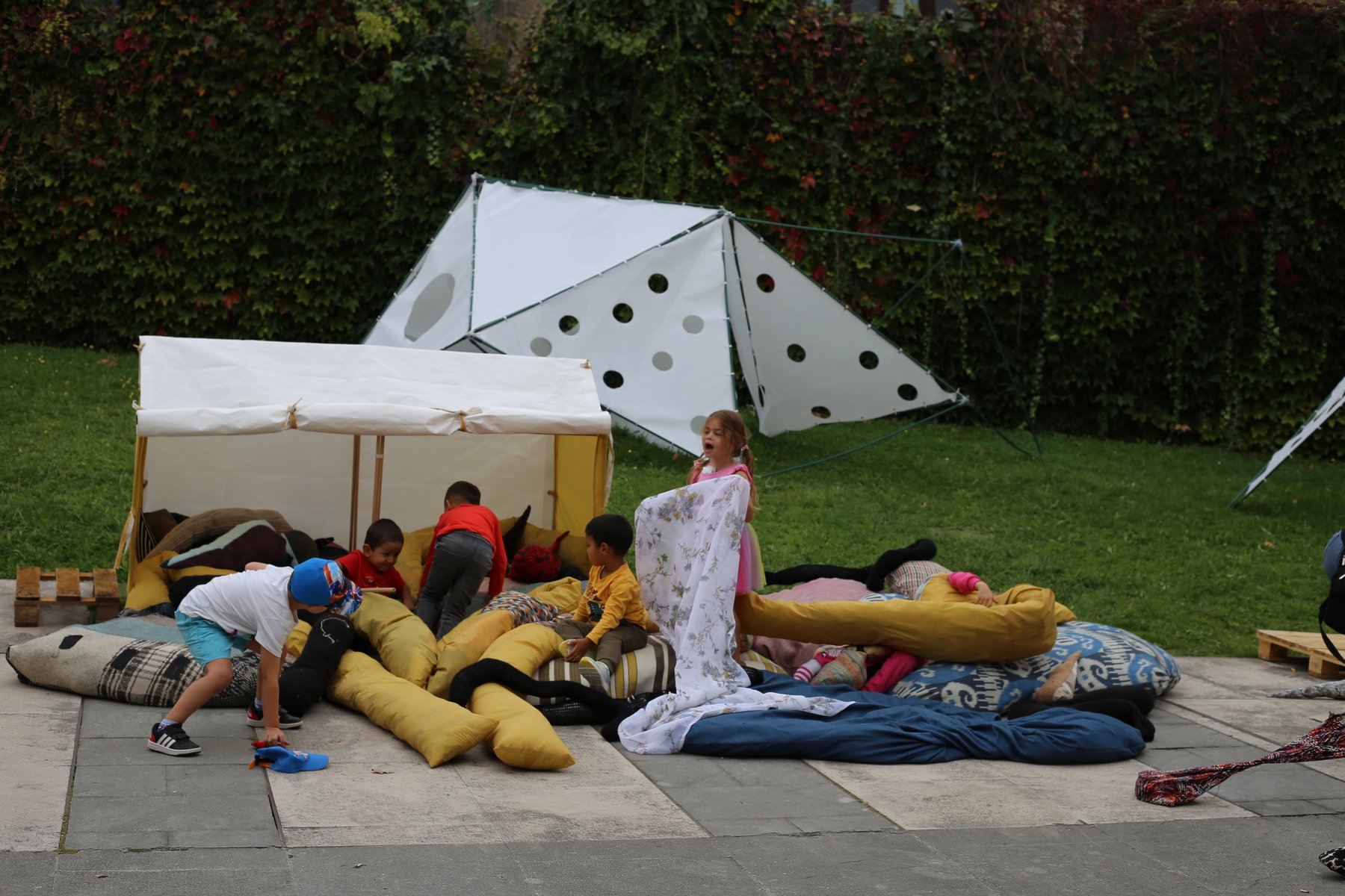 Grupo de niños reunido sobre una topografía de grandes piezas textiles blandas.