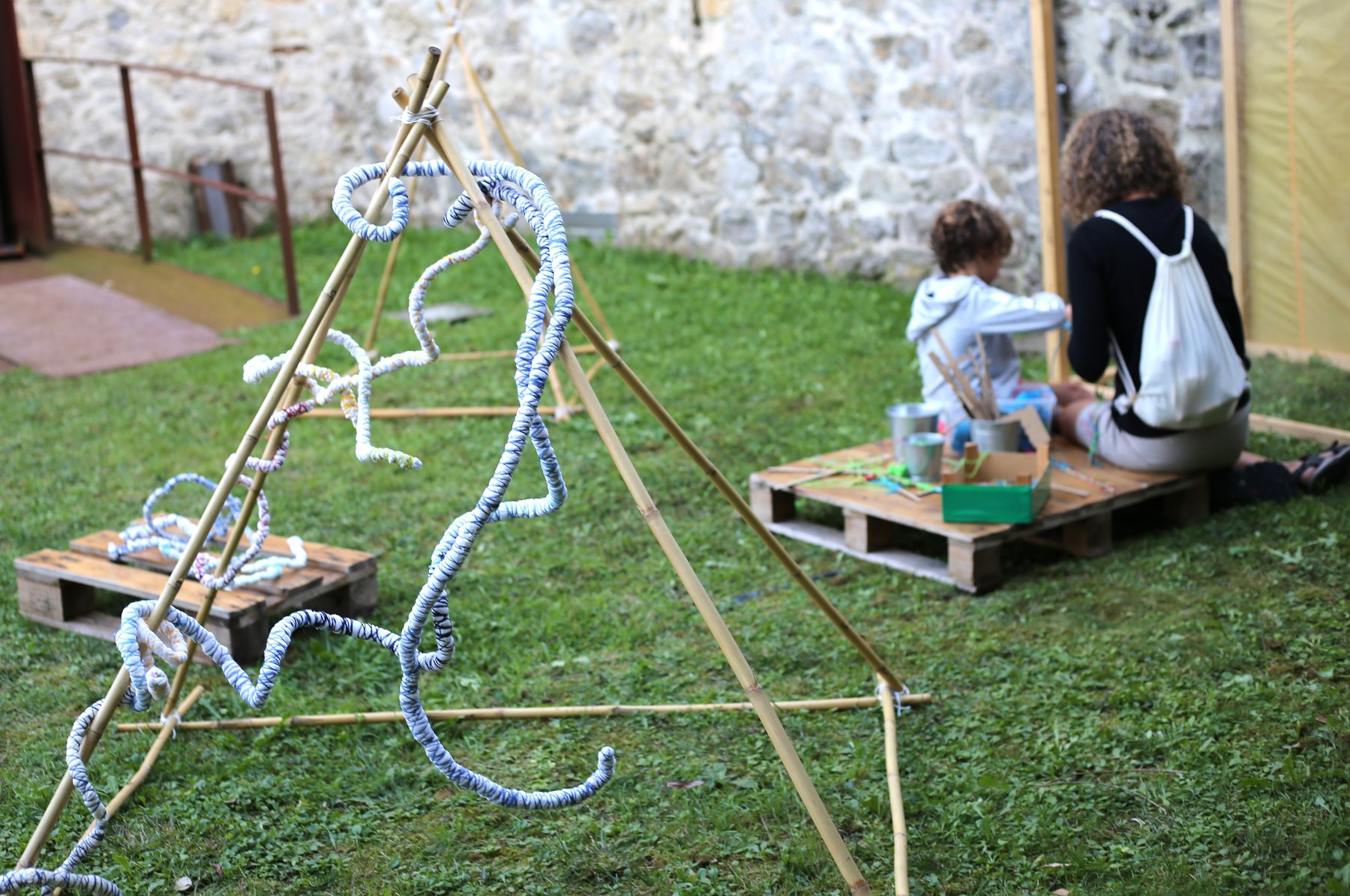 Niñas explorando formas textiles suspendidas en estructuras de bambú.