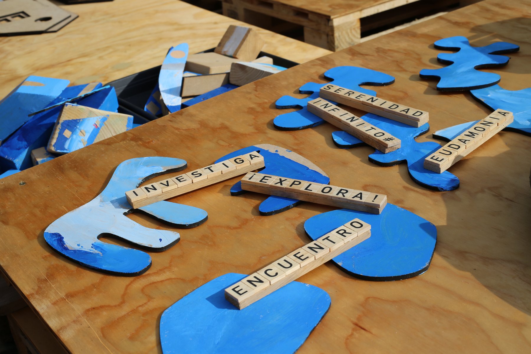 Palabras y formas azules componen un mensaje sobre una superficie de madera.