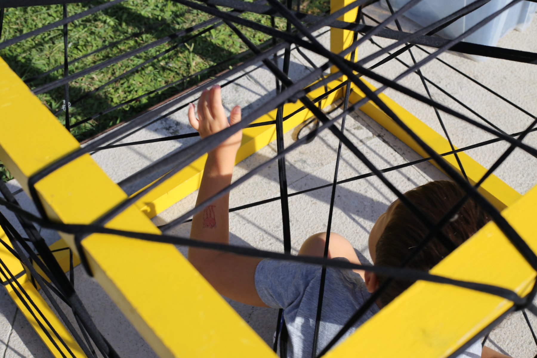 Una mano explora el entramado de una estructura geométrica amarilla y negra.