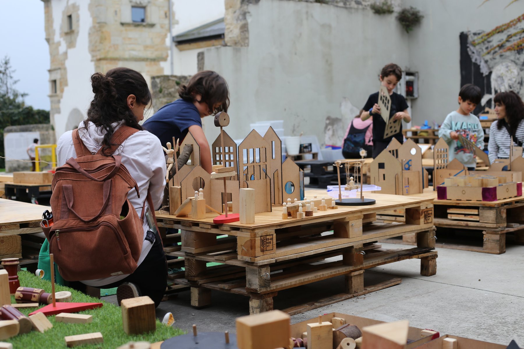 Familias construyen juntas una ciudad con piezas de madera.