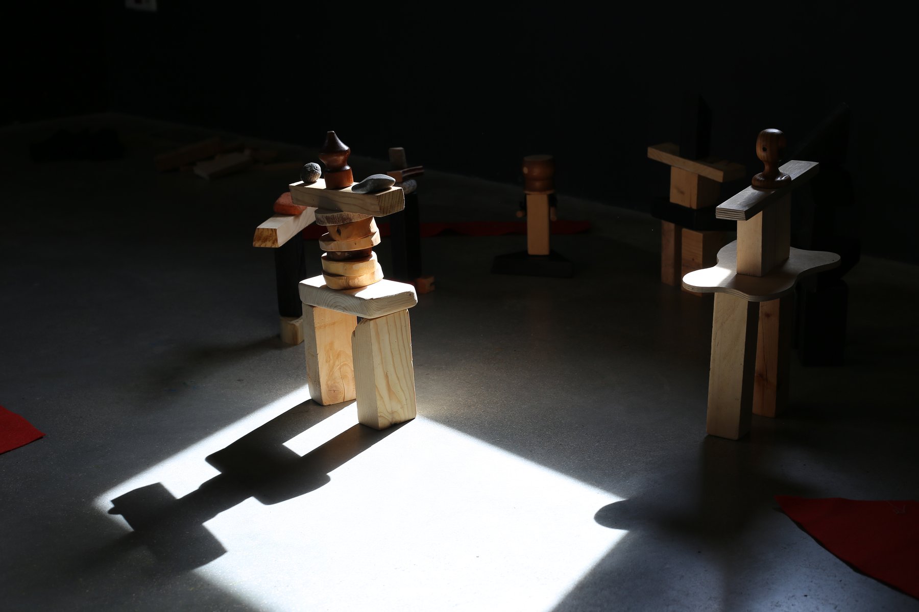 Personajes de madera iluminados sobre una superficie oscura.