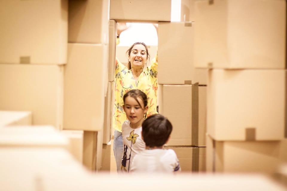 Niñas y niños miran a través de una construcción de cartón.