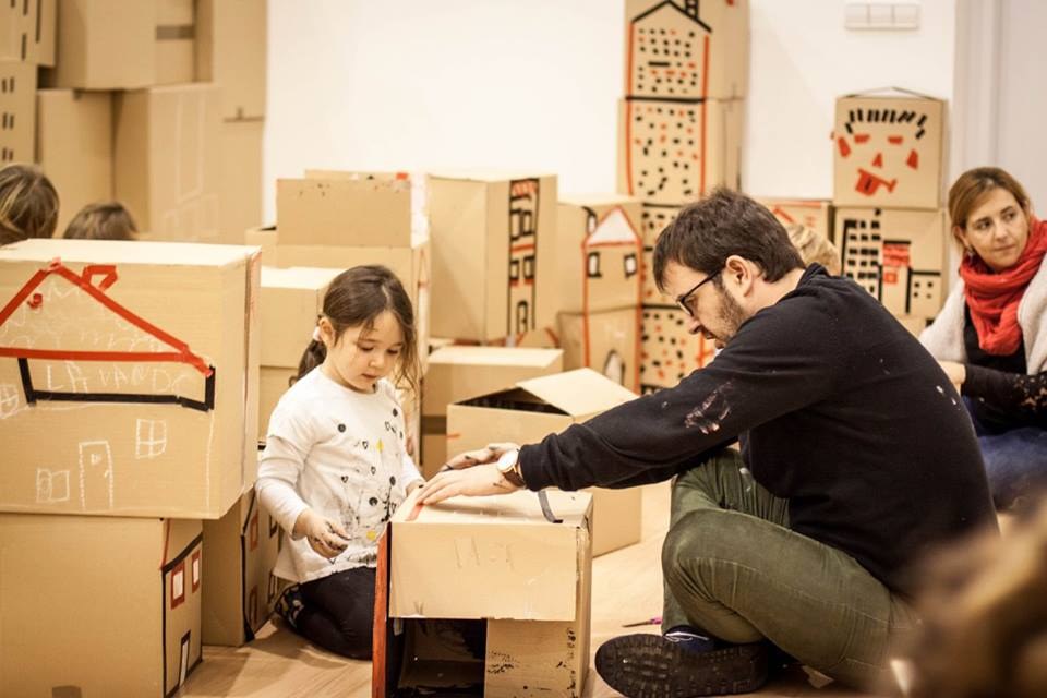 Adulto y niña dibujan sobre una construcción de cartón.