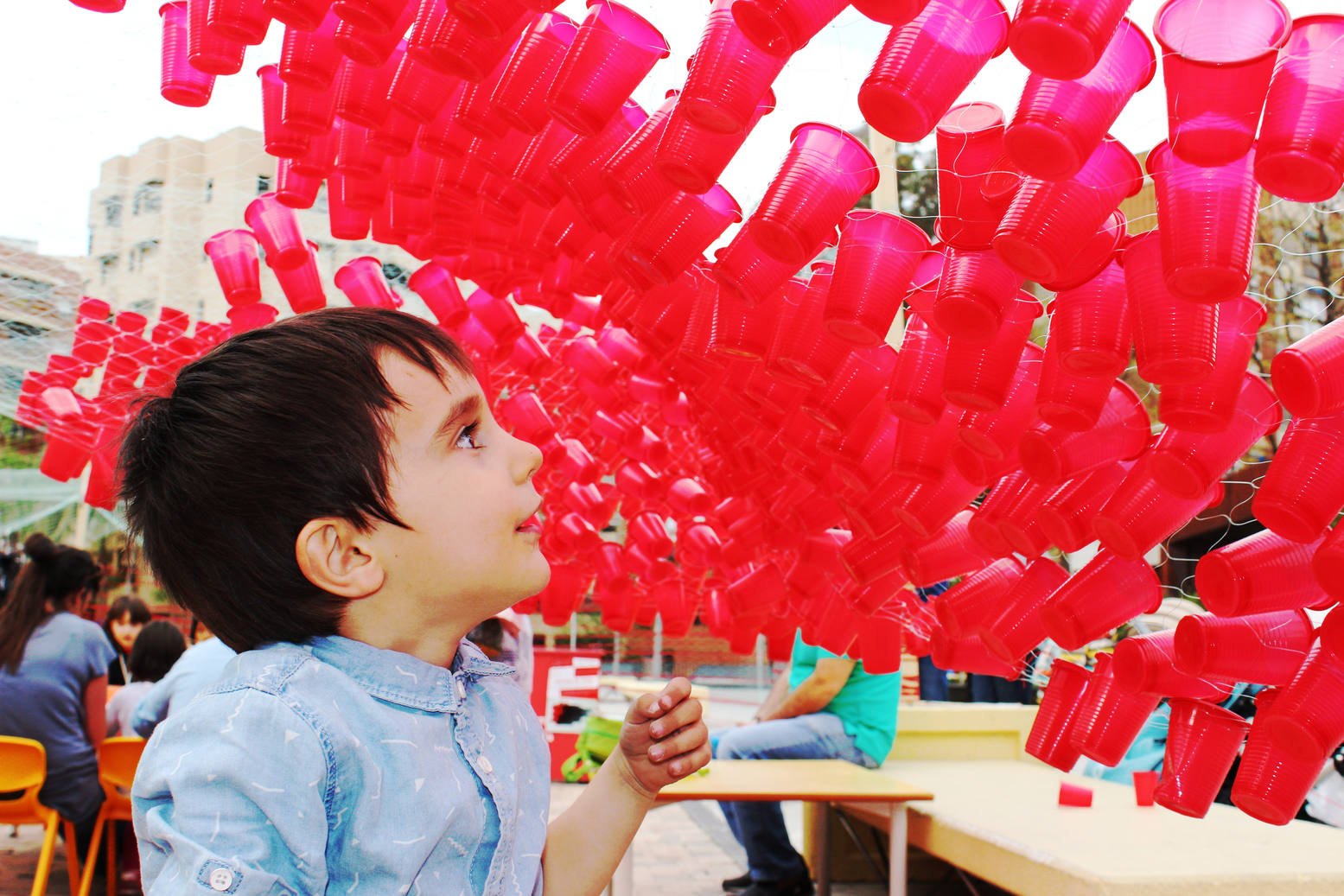 Un niño observa la estructura de vasos y materiales rojos durante la actividad.