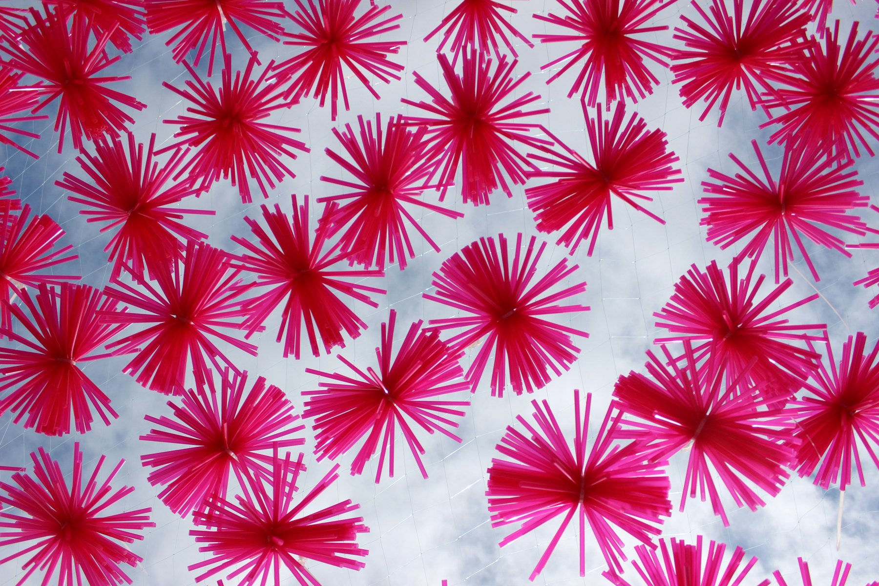 Cielo de piezas rosas suspendidas visto desde debajo de la instalación.