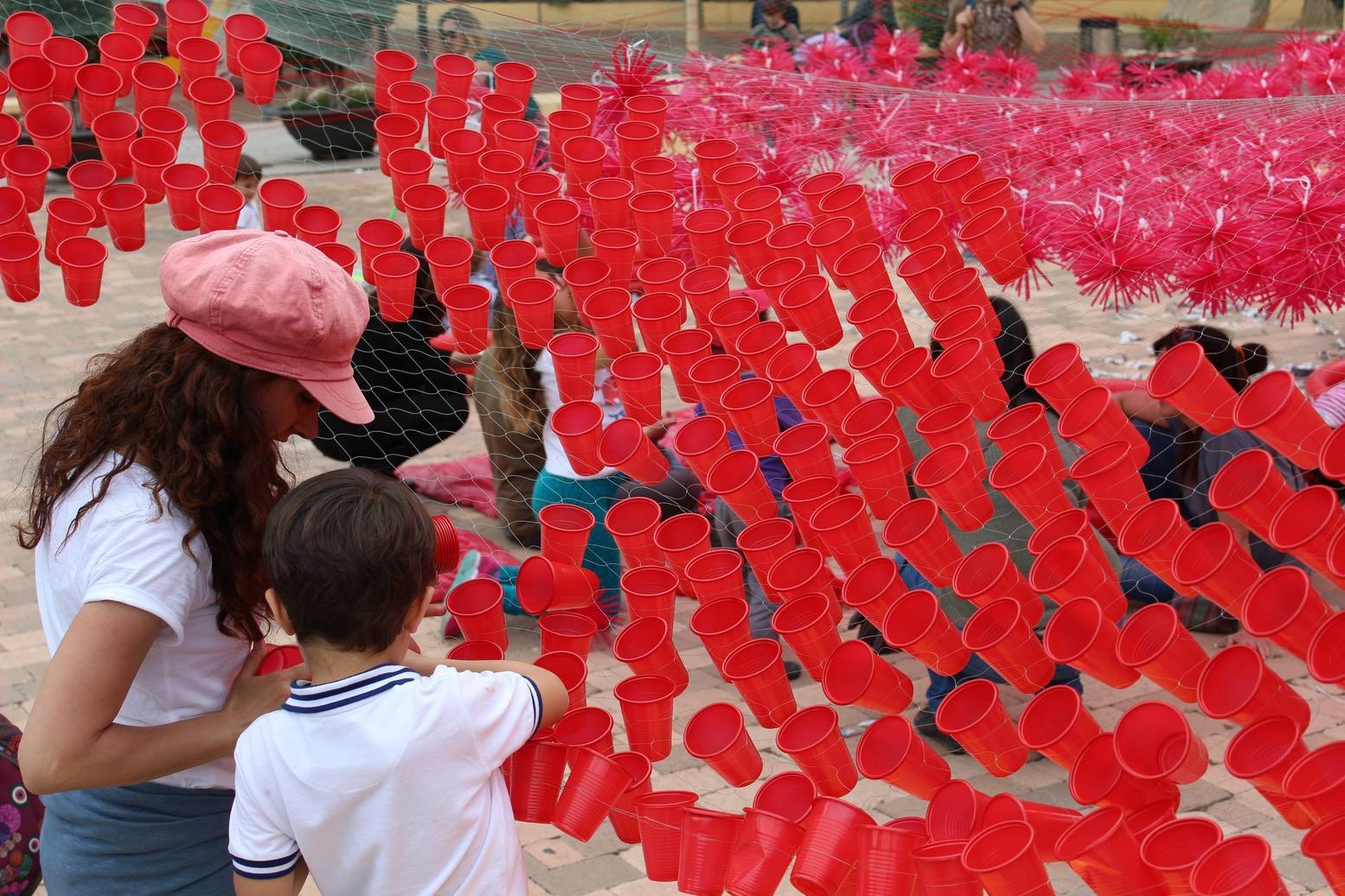 Superficie curva de vasos rojos atravesada por participantes durante la instalación.