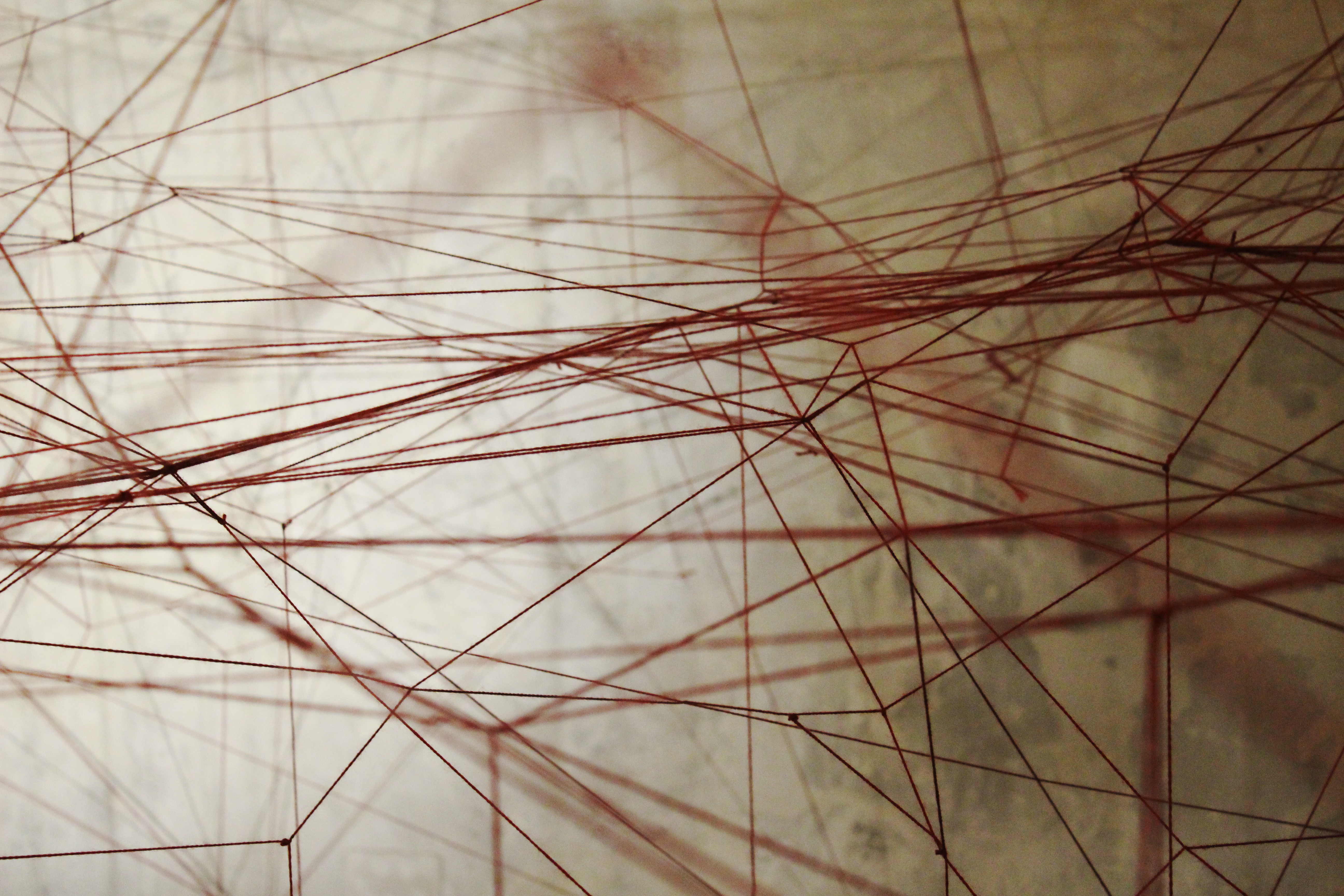 Tramas de hilo rojo ocupando el muro como plano de dibujo espacial.