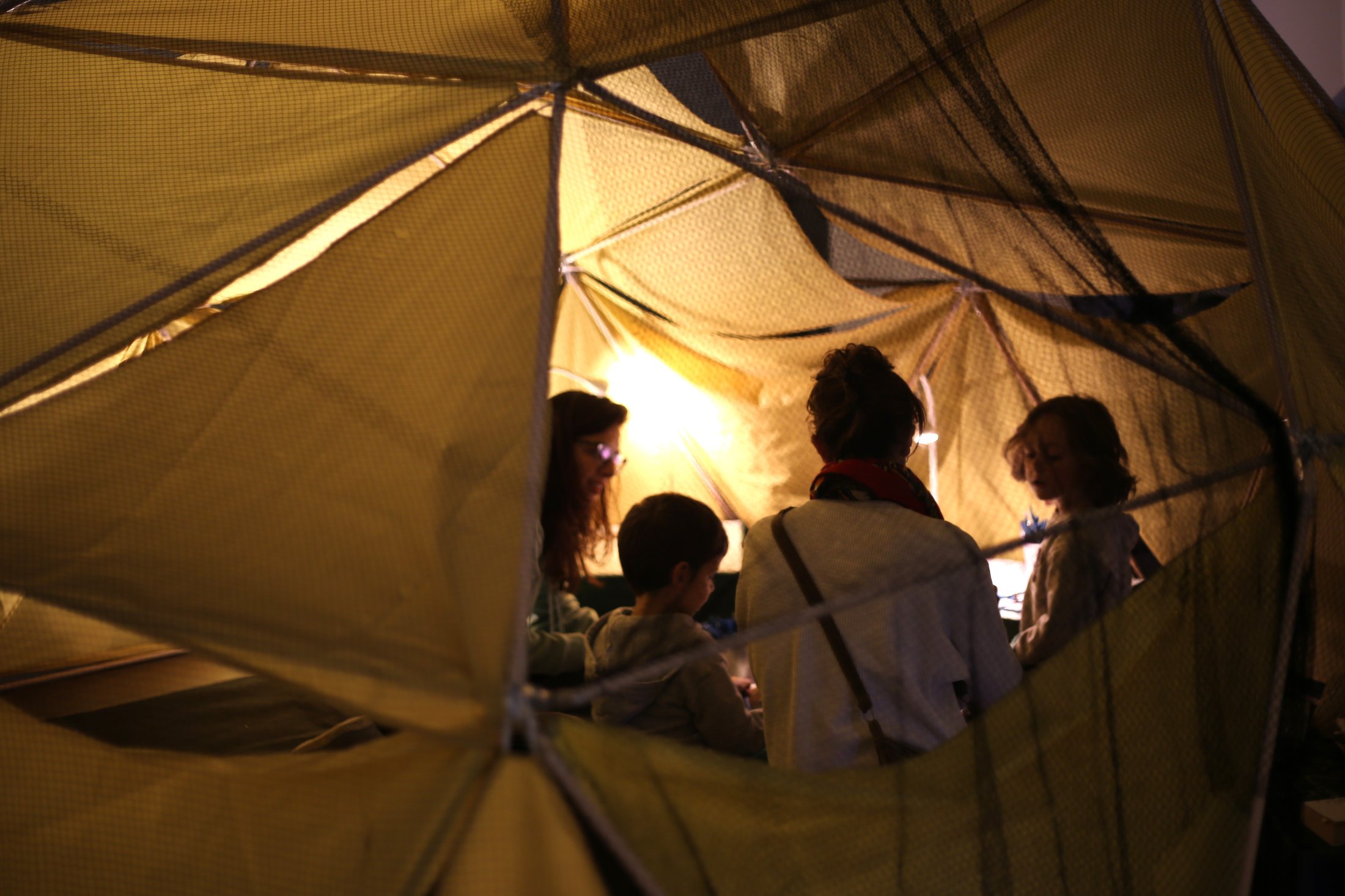Niñas y familias habitan el interior luminoso de una cabaña.