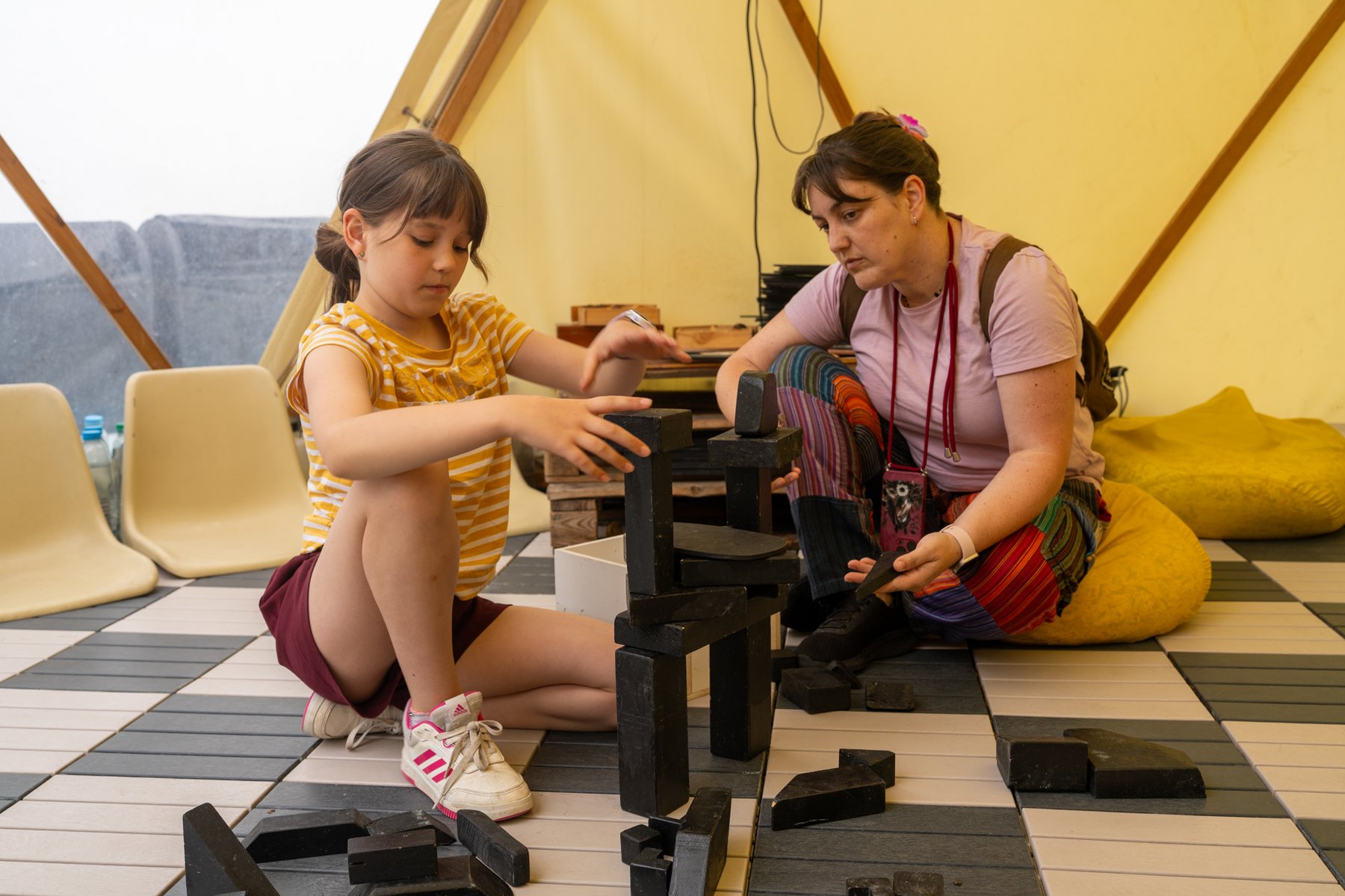 Una niña y una adulta construyen con piezas de madera.