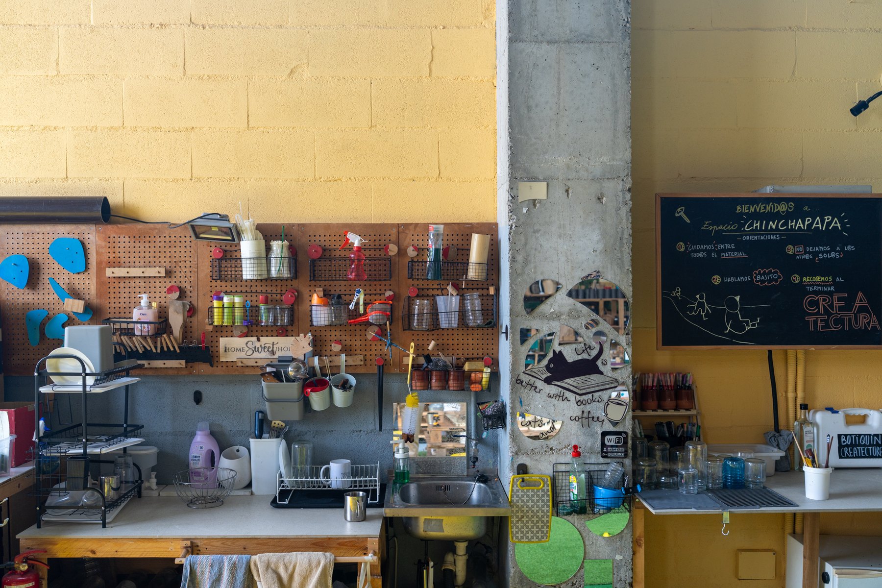 Rincón de materiales y utensilios junto al muro amarillo.